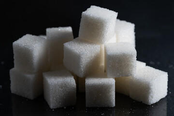 Pile of refined sugar cubes dark background.