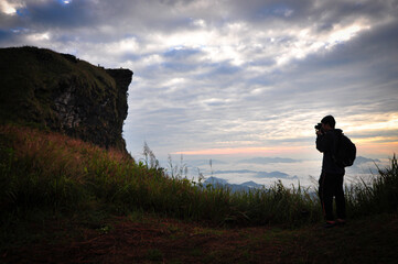 Silhouette of man taking photo famous mountain and landmark at Phu chi fa, Chiang Rai, Thailand