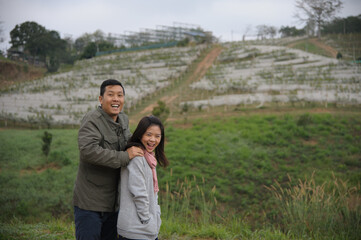 Asian couple jumping for taking photo with happy mood and natural hill background