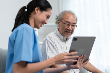 Fototapeta premium Asian nurse showing health checkup report to grandfather and giving advice. medical assisted living visit senior patient at home. Home nursing and healthcare caregiver concept