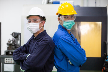Asian factory worker and manager wearing protective mask standing back to back in arms crossed position at industrial construction