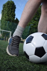A young man in sportswear is playing soccer, training on a football pitch in the morning. Dedication and passion for the sport, the essence of morning exercise and practice outdoors