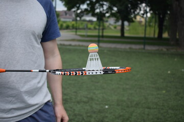 A young man in sportswear is playing badminton, training on a sport field in the morning. Dedication and passion for the sport, the essence of morning exercise and practice outdoors