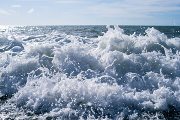 Sea wave close-up, water splash in the sea, sea foam against the sky on a summer sunny day