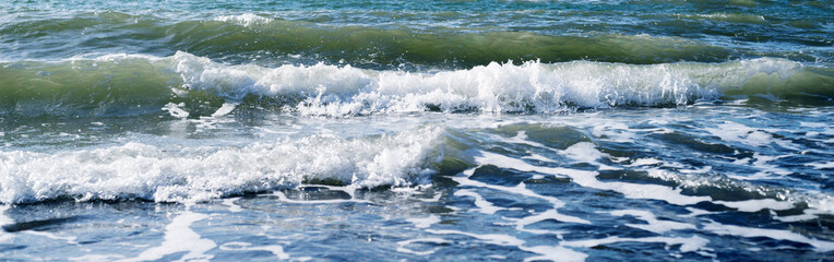 Sea wave close-up, splash of water in the sea, sea foam on a summer sunny day. Blue sea texture with waves