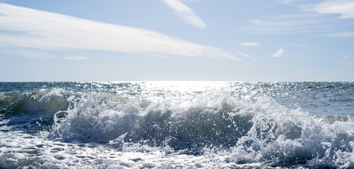 Sea wave close-up, water splash in the sea, sea foam against the sky on a summer sunny day