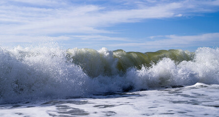 Sea wave close-up, water splash in the sea, sea foam against the sky on a summer sunny day