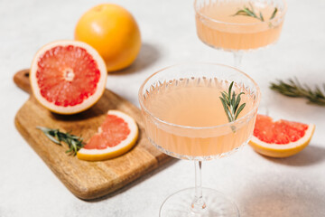 Elegant grapefruit and rosemary cocktails served in crystal glasses with fresh grapefruit slices, set against a light background. Perfect for summer gatherings and holiday party. Refreshing mocktail.