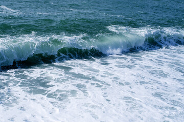 Sea wave close-up, splash of water in the sea, sea foam on a summer sunny day. Blue sea texture with waves