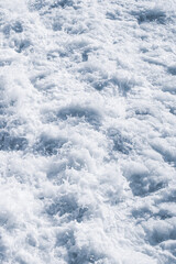 White sea foam close-up, splash of water in the sea on a summer sunny day, top view. Marine texture background.