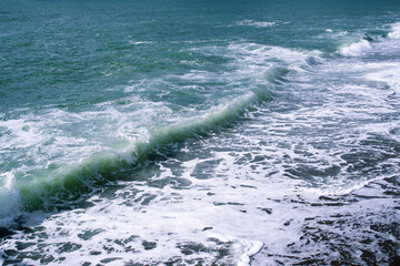 Sea wave close-up, splash of water in the sea, sea foam on a summer sunny day. Blue sea texture with waves