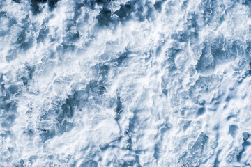 White sea foam close-up, splash of water in the sea on a summer sunny day, top view. Marine texture background.