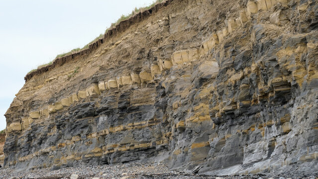 View of cliff with layers of different coloured rocks at popular fossil hunting destination of Kilve Beach on the Jurassic Coast in England UK