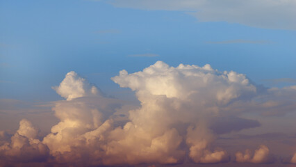 over the clouds, cumulus cloudscape in the evening sun on blue sky, weather background with copy...