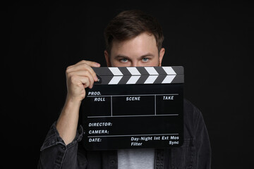Making movie. Man with clapperboard on black background