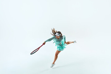 Young woman, tennis player in mint-green outfit, mid-serve, with ball and racquet in action against white studio background. Concept of professional sport, championship, active lifestyle, tournament.