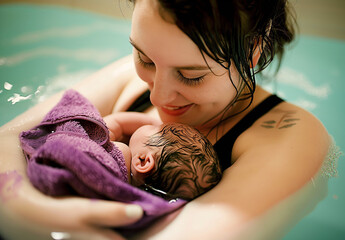 Water birth, a woman holding her newborn baby in her arms, joyful expression, labour in water.