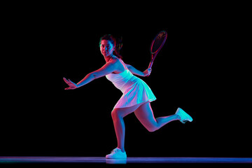 Female tennis player in white outfit captured mid-swing in neon light against black studio background. Concept of professional sport, championship, active lifestyle, tournament. Ad