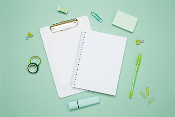 Creative flat lay mockup design of workspace. Top view composition with white notebook, to do list and stationery on green background