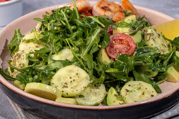 Salad with cucumbers and arugula, shrimp and cherry tomatoes in a light sauce.