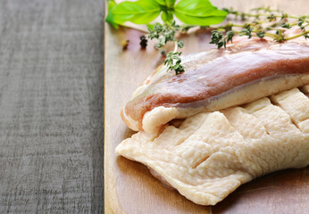 raw duck fillet with aromatic herbs on a wooden board