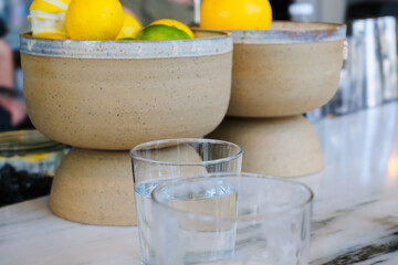ceramic bowls with citrus fruits and glasses of fresh clean water, healthy refreshment antioxidant at bar table