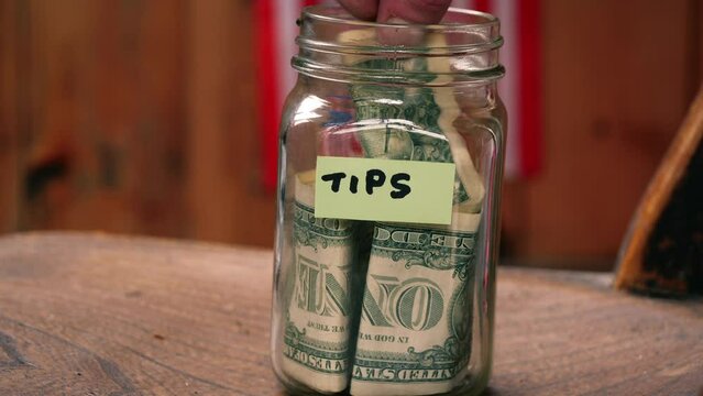 Putting dollars into a tip jar 