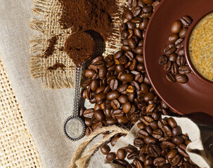 A cup of Americano against a background of ground grains and burlap. Arabica is the most common coffee variety.