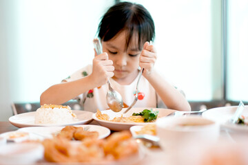 Cute asian kid girl eating rice with 
omelet by self. Copy space. Learning Concept .