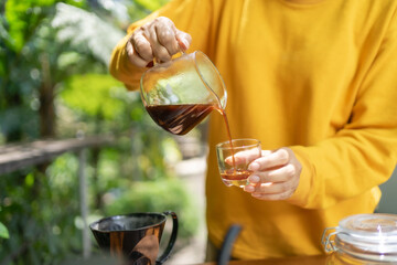 pouring black coffee from a glass carafe into a glass.