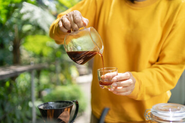 pouring black coffee from a glass carafe into a glass.