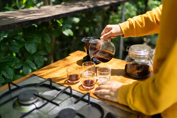 pouring black coffee from a glass carafe into a glass.