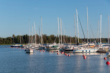 Fototapeta premium Marina sea port, sailboats moored at the dock and reflected in the sea, harbor, sea and blue sky, sunny day