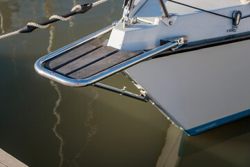Wooden bowsprit on the moored sailboat in the harbor, calm water in marina