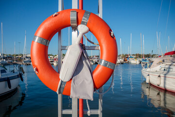 SOS nautical emergency concept. Lifebuoy, orange lifebelt put on vertical ready for using. Close up...