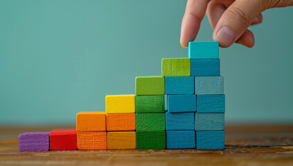 Hand placing wooden blocks in ascending order to form a colorful staircase