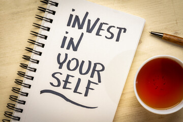 Invest in yourself motivational advice or reminder - handwriting in a spiral notebook with tea, personal development and healthy lifestyle concept