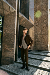 Red-haired young man in debonair suit walking up city steps.