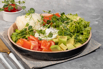 Salad bowl with rice, salmon, tomatoes, cucumbers and avocado. Poached egg.