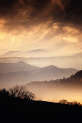 mist and mountains in autumn with golden light at sunset