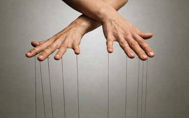 A puppeteer's hands with strings on each finger.