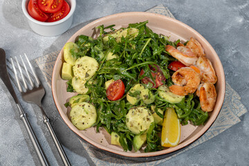 Salad with cucumbers and arugula, shrimp and cherry tomatoes in a light sauce.