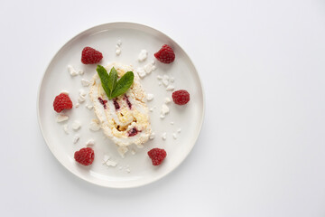 Raspberry meringue roll on a white plate close-up. Dessert on a white background. Breakfast decorated with berries