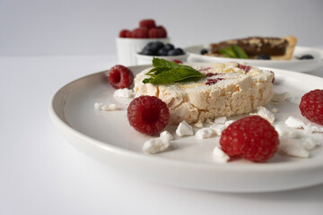 Raspberry meringue roll on a white plate close-up. Dessert on a white background. Breakfast decorated with berries