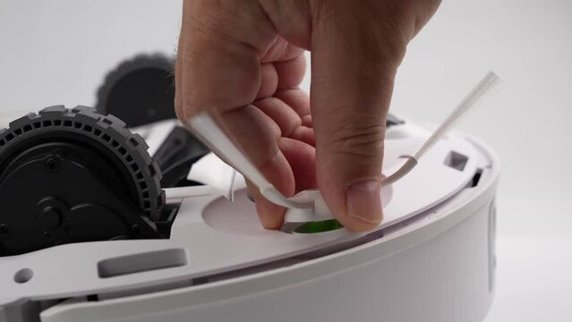 A person is working on a robot. The robot is white and has wheels