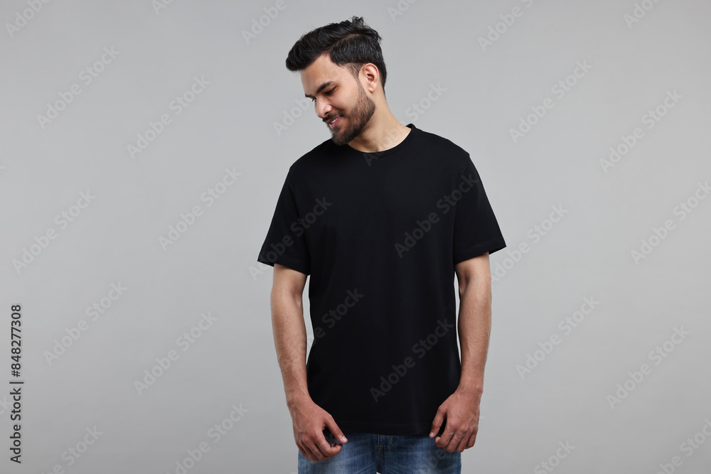 Wall mural Smiling man in black t-shirt on grey background - Wall murals