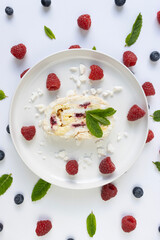 Raspberry meringue roll on a white plate close-up. Dessert on a white background. Breakfast decorated with berries