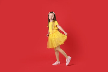 Cute little girl dancing on red background