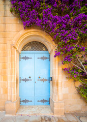 Beautiful attraction in Mdina (the Silent city). Fantastic view a yellow house wall with light blue door and purple flowers