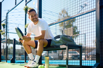 Fototapeta premium Happy athlete relaxing after playing paddle tennis outdoors.